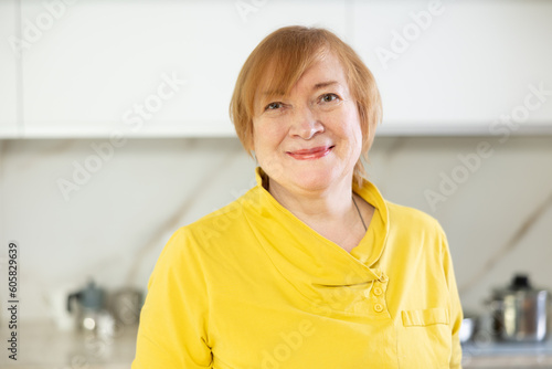 Happy mature woman cooking in her kitchen with radiant smile