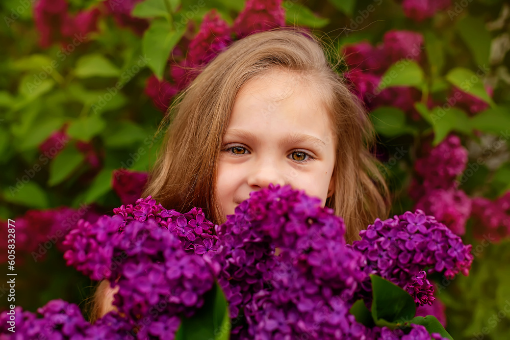 a beautiful happy smiling blonde girl with long hair in a pink dress with a purple bouquet of lilacs in her hands stands against the background of a lilac bush a beautiful happy smiling blonde girl with long hair in a pink dress with a purple bouquet of lilacs in her hands stands against the background of a lilac bush