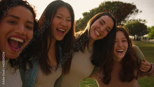 Four happy girls laughing and hugging while standing on rain