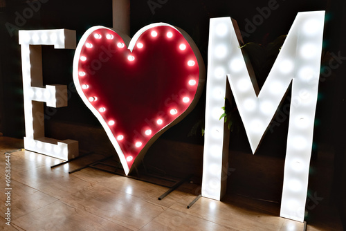 a lighted sign with the letters E and M and a heart in the middle