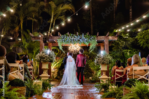 a hallway with a wooden deck and a pergola in the background with a couple at their wedding