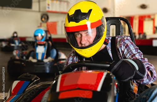Portrait of glad man driving racing car at kart circuit