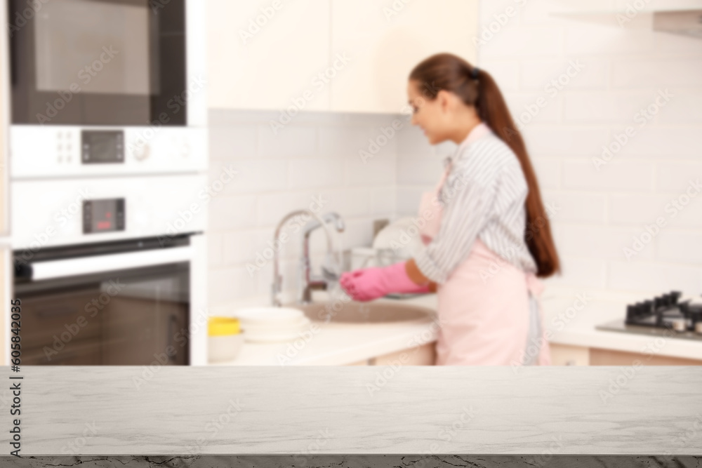 Woman doing washing up in kitchen, focus on empty table Woman doing washing up in kitchen, focus on empty table