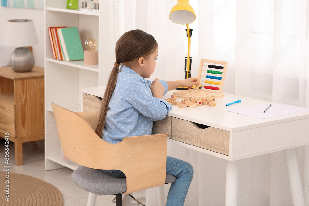 Girl with colorful abacus and wooden cubes at desk in room. Home workplace Girl with colorful abacus and wooden cubes at desk in room. Home workplace