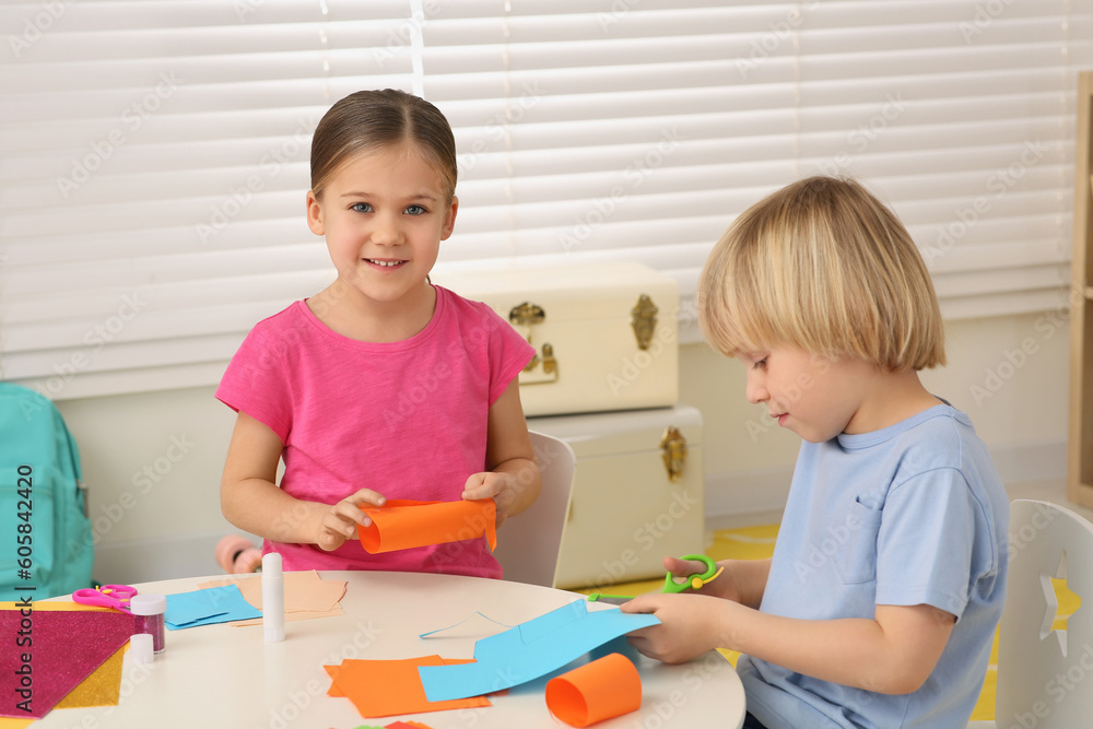 Cute children making paper toys at desk in room. Home workplace Cute children making paper toys at desk in room. Home workplace