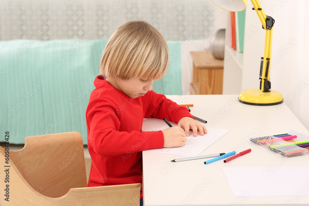Little boy drawing at desk in room. Home workplace Little boy drawing at desk in room. Home workplace