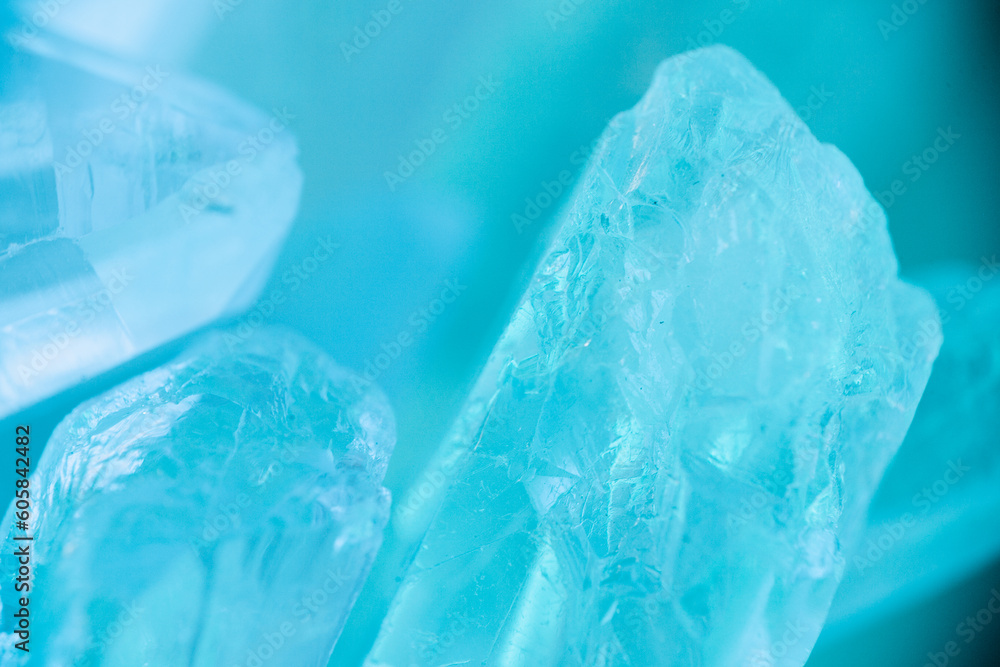 Fototapeta premium Rock crystal macro in blue light.transparent quartz crystals background in blue tones.texture of gemstone. crystals of natural transparent stone rock.Texture of natural stone Rock crystal