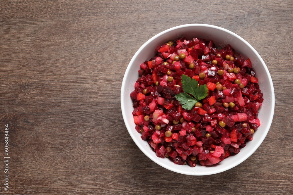 Bowl of delicious fresh vinaigrette salad on wooden table, top view. Space for text