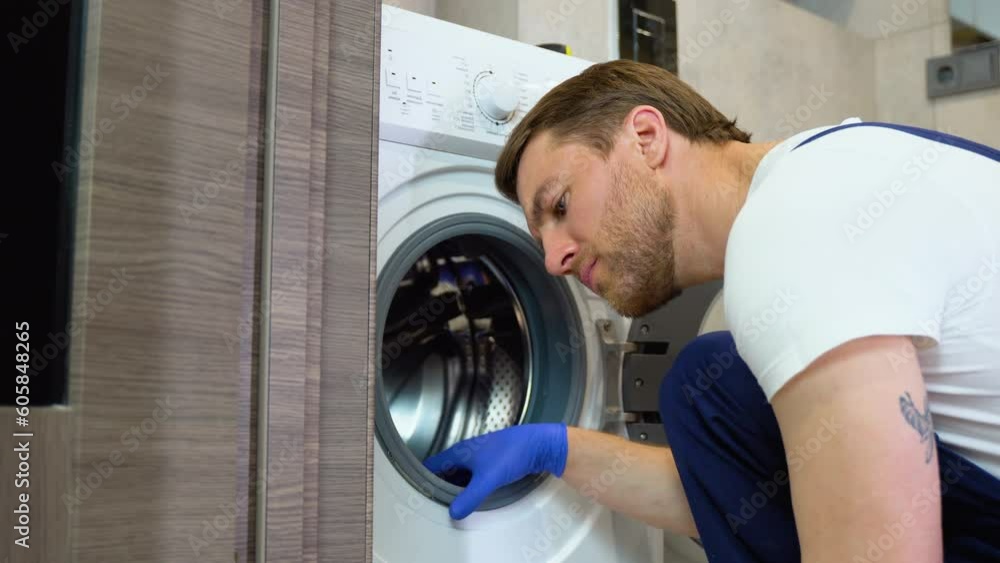 A man in blue gloves cleans a dirty, moldy rubber seal on a washing