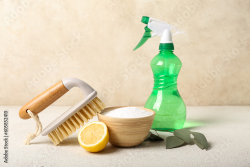 Photos Bowl of baking soda, sprayer, cleaning brush and lemon on light table