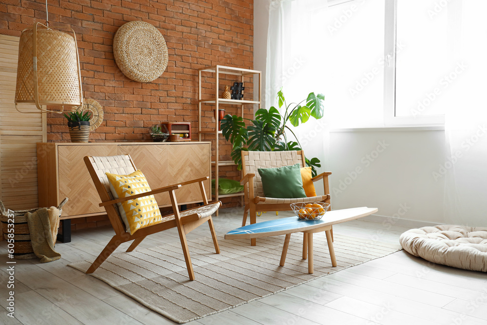 Cozy wooden armchairs with cushions and fruit basket on surfing board in interior of living room - obrazy, fototapety, plakaty 