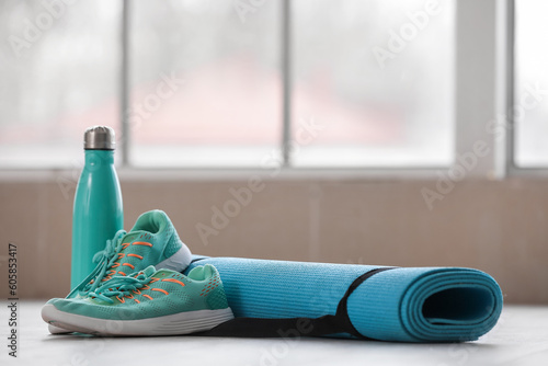 Yoga mat with sneakers and bottle of water in gym