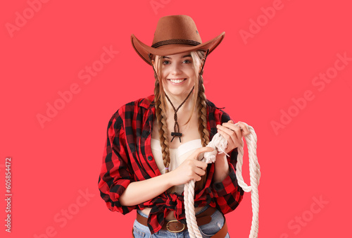 Foto Young cowgirl with lasso on red background