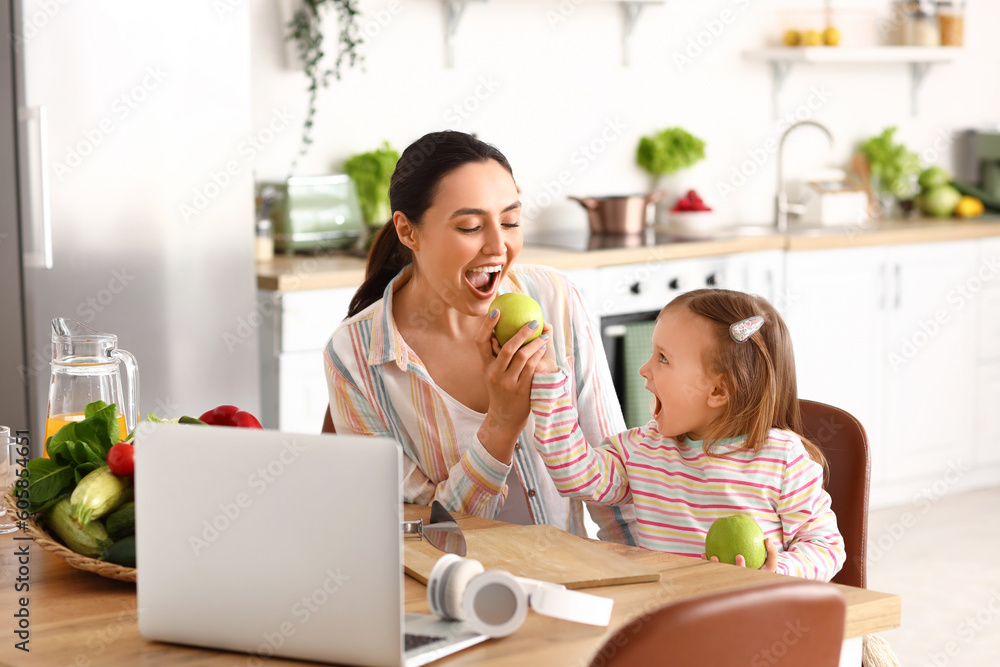Little girl with her mother and apples in kitchen Little girl with her mother and apples in kitchen