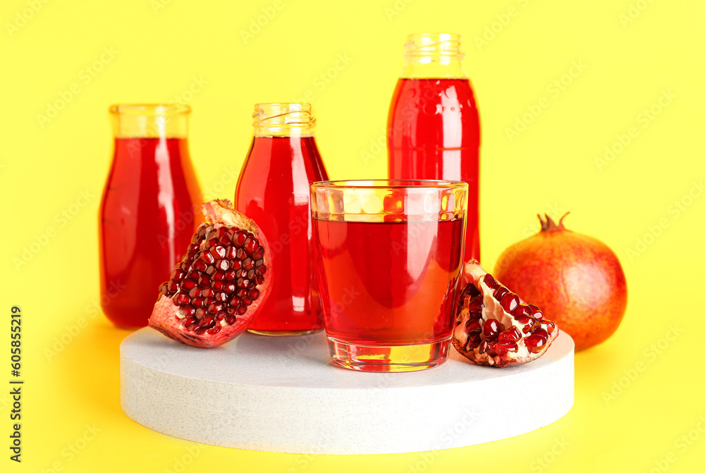 Bottles and glass of fresh pomegranate juice on yellow background Bottles and glass of fresh pomegranate juice on yellow background