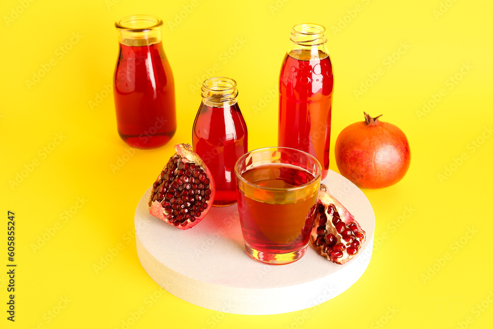 Bottles and glass of fresh pomegranate juice on yellow background Bottles and glass of fresh pomegranate juice on yellow background