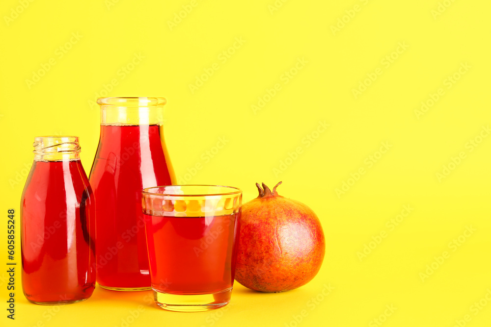 Bottles and glass of fresh pomegranate juice on yellow background Bottles and glass of fresh pomegranate juice on yellow background