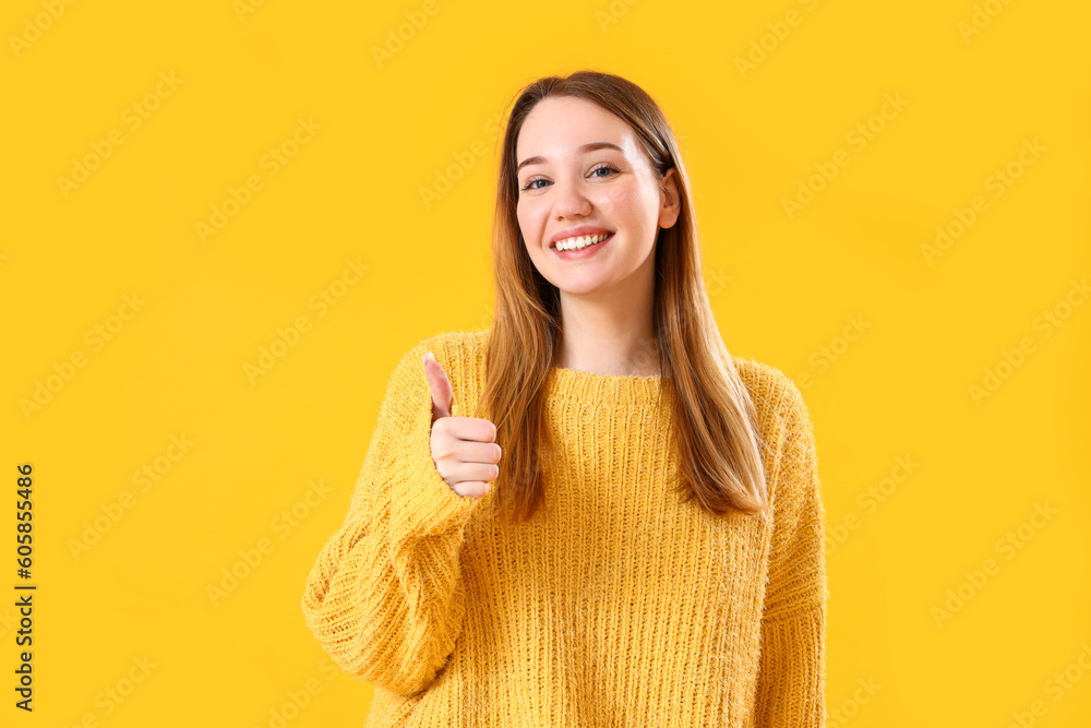 Beautiful young woman showing thumb-up on yellow background Beautiful young woman showing thumb-up on yellow background