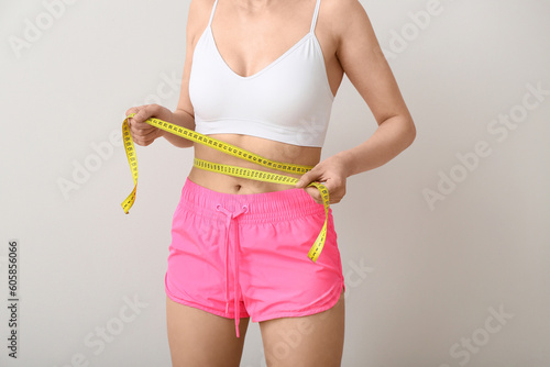 Young woman with measuring tape on white background. Diet concept © Pixel-Shot