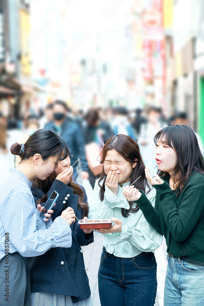 Obraz premium 食べ歩きをする女性4人