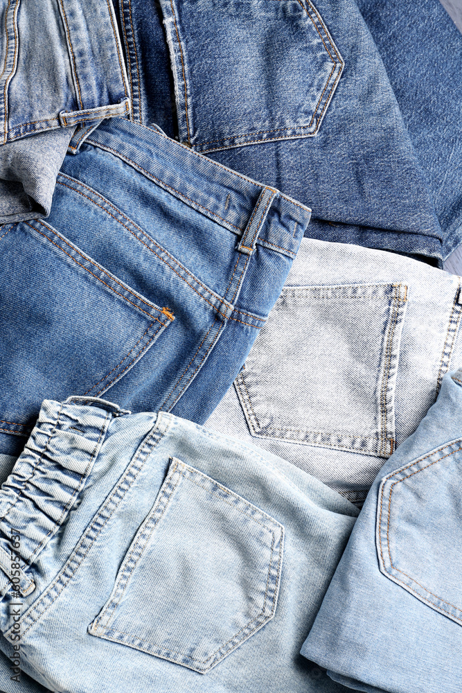 Different stylish denim jeans as background, closeup Different stylish denim jeans as background, closeup