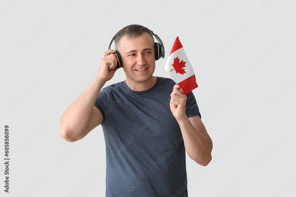 Mature man in headphones with flag of Canada on light background Mature man in headphones with flag of Canada on light background