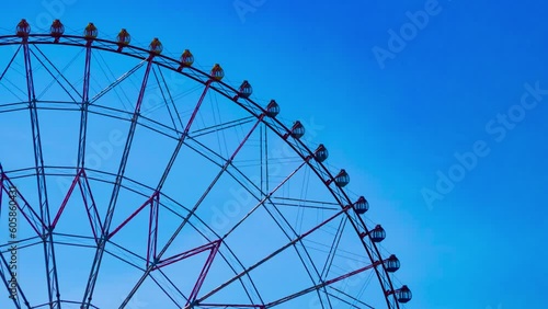 A timelapse of ferris wheel at the park behind the blue sky telephoto shot zoom photo