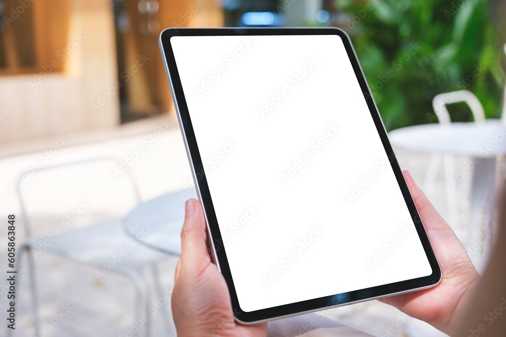 Mockup image of a woman holding digital tablet with blank white desktop screen in the outdoors cafe