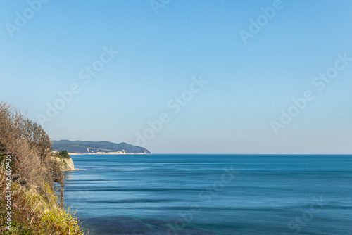 beach and sea. Blue Sea and Cliff on the Seaside. Seaside with cliff and blue sky on the ocean. blue waves on the sea. sky over the sea and cliff. green trees on cliff. vocation on ocean. summer time.
