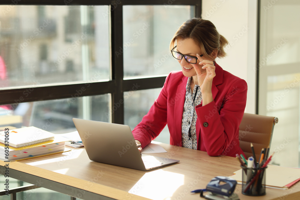 Obraz premium Positive woman takes off glasses with hand looking at screen