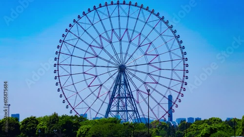 A timelapse of moving ferris wheel at the park behind the blue sky photo