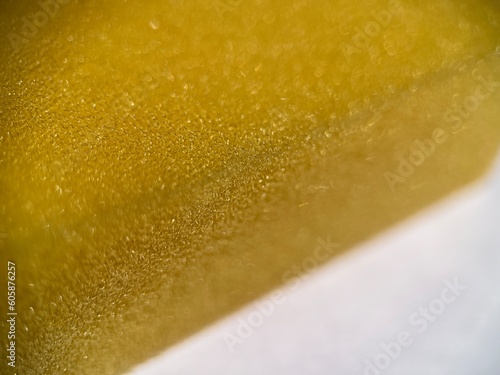 Selective focused view of yellow sponge texture isolated on white background. Macro photography.