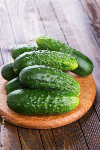 Fresh organic cucumbers on board on wooden table. Selective focus,vertical. Natural/organic/bio/healthy products.