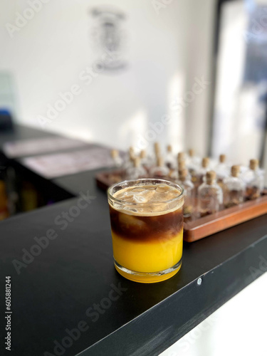 A glass of orange coffee on a black table inside the cafe