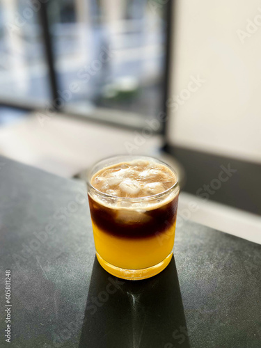 A glass of orange coffee on a black table inside the cafe