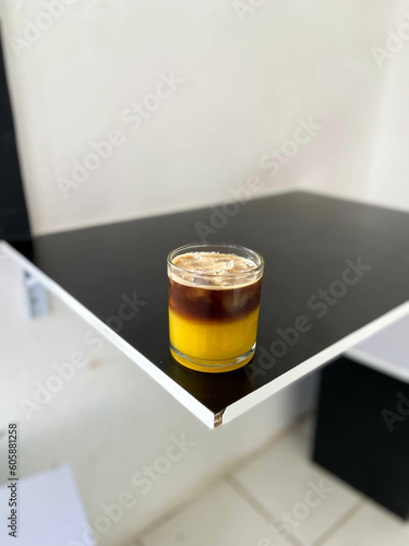 A glass of orange coffee on a black table inside the cafe