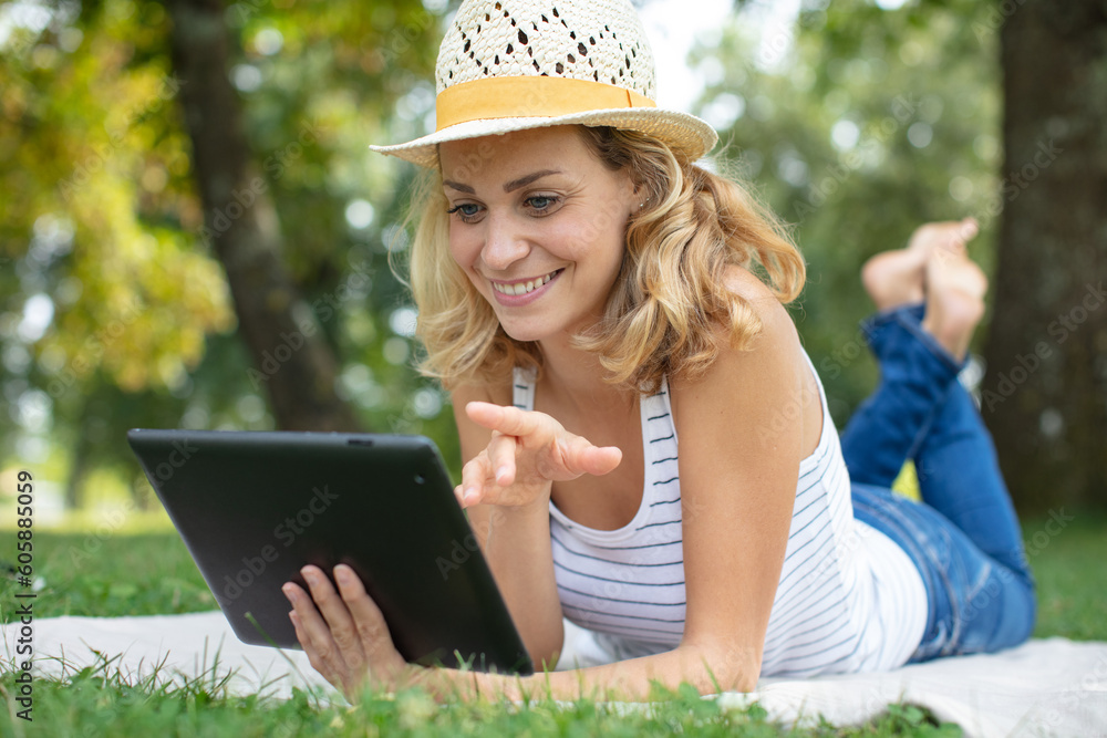 happy young girl on the grass and using a tablet