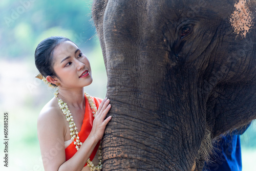 Relationship between Asian people and elephant, Thai lady beautiful dressing traditional northern style touching elephant's trunk, hug elephant with love