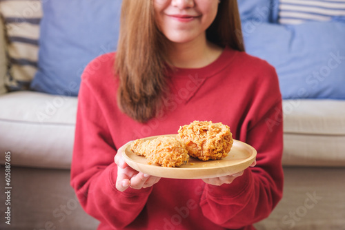 Closeup image of a young woman holding a plate of fried chicken at home