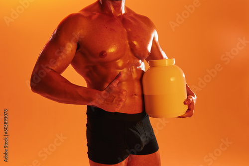 Man bodybuilder boxer with naked torso with abs holding a can of muscle growth pills, steroids, doping, protein. Advertising, sports, active lifestyle, competition, challenge concept. 