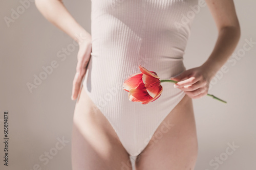 Gynecology, menstruation, concept of woman genital health. Gynecology concept. Young woman holds tulip near bikini zone. Gynecology and underwear, women health. innocence and loss of virginity photo