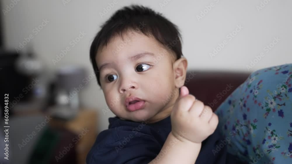 A happy young Asian baby boy being held in his mother’s arms as he chews on food. Slow Motion A happy young Asian baby boy being held in his mother’s arms as he chews on food. Slow Motion