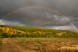 Landscape with plantation of young poplars, forests and sky with rainbow, on the banks of the Bernesga River, León, Spain.