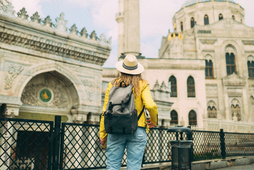 Young beautiful girl traveler in a hat with a backpack