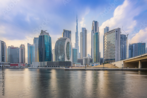 Dubai with skyscrapers and Burj Khalifa in the evening. Skyline with a cloudy sky in the evening mood. Waterfront in Dubai Harbour. Houses with glass front and concrete facades architecture © Marco