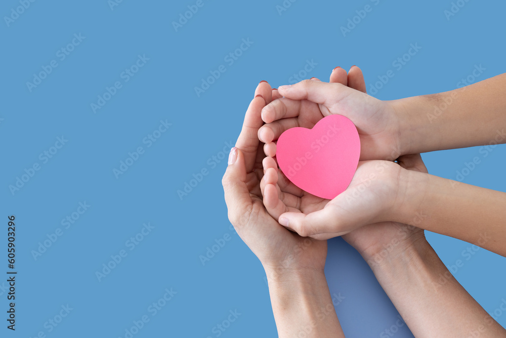 Heart in baby and mother hands isolated on blue background..Young woman and child holding heart in hands top view. Happy family relationships, love to mom, mother day, protect concept.Space for text.. Heart in baby and mother hands isolated on blue background..Young woman and child holding heart in hands top view. Happy family relationships, love to mom, mother day, protect concept.Space for text..