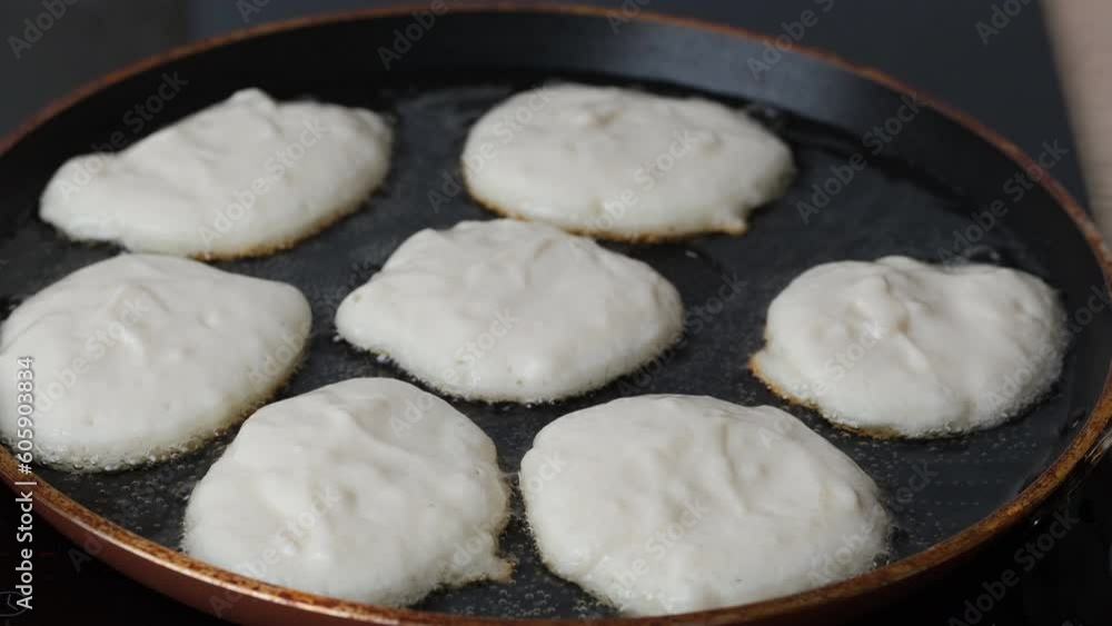 The cook prepares small pancakes in a frying pan. Healthy food concept. The cook prepares small pancakes in a frying pan. Healthy food concept.