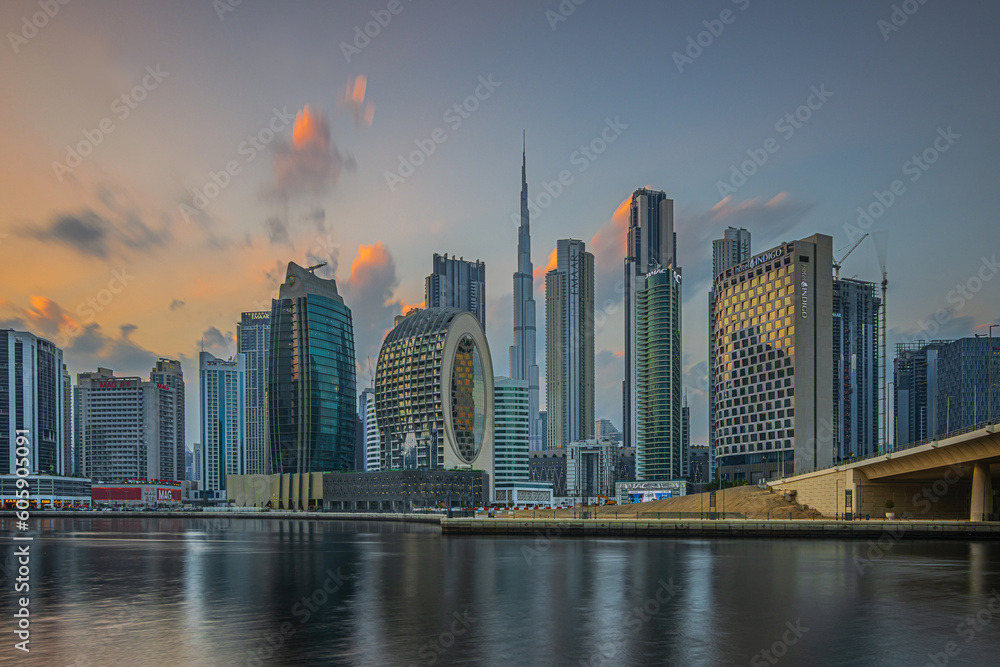 Sunset in Dubai. Evening sun with clouds over city skyline of United Arab Emirates. City center with skyscrapers of business and office buildings in the evening at sunset