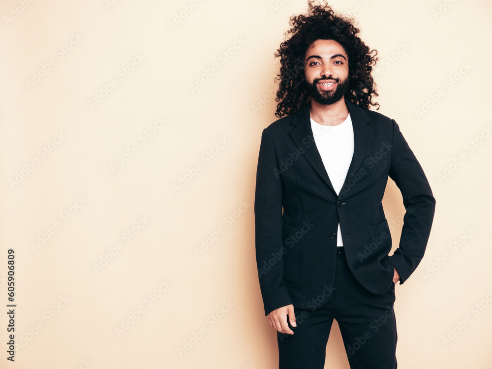 Handsome smiling hipster model. Unshaven Arabian man dressed in summer suit jacket clothes. Fashion male with long curly hairstyle isolated on beige in studio. Cheerful and happy Handsome smiling hipster model. Unshaven Arabian man dressed in summer suit jacket clothes. Fashion male with long curly hairstyle isolated on beige in studio. Cheerful and happy