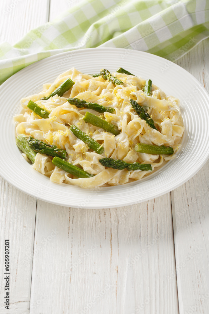 Lemony Asparagus Pasta fettuccine with parmesan cream sauce closeup on the plate on the wooden table. Vertical